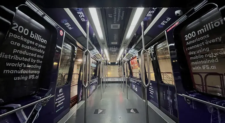 Interior of a subway train wrapped in IFS.ai advertisements highlighting sustainability and technology statistics.